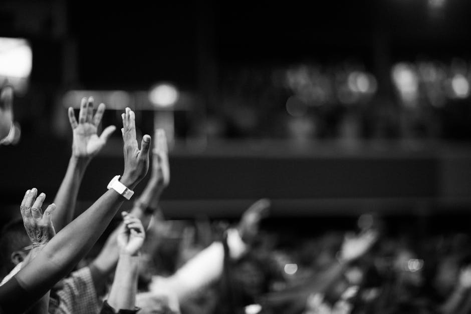 Black and white image of audience with hands raised, capturing concert energy. Black and white image of audience with hands raised, capturing concert energy.